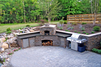 A patio with an outdoor kitchen island and a pizza oven